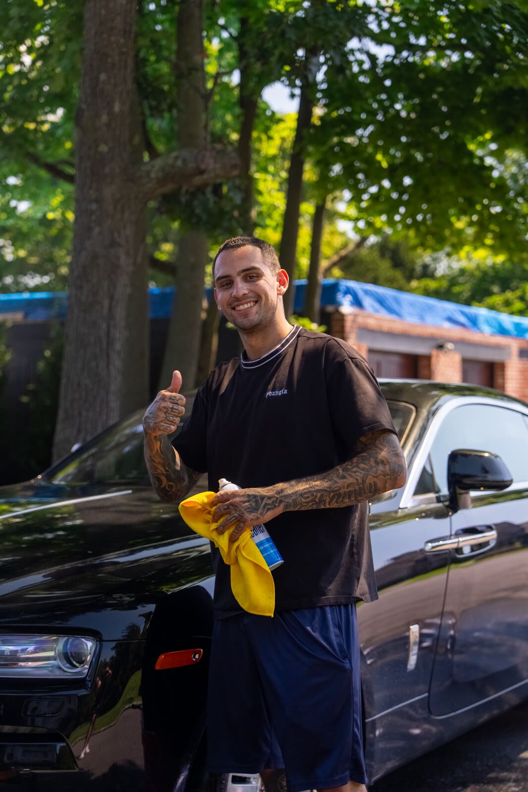Spark & Spin detailer standing next to a finished black Audi, giving a thumbs-up